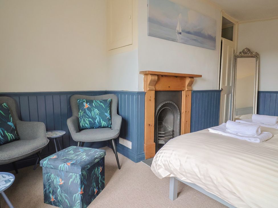 A bedroom with a bed and two armchairs at 5B Bridge Street in Lyme Regis