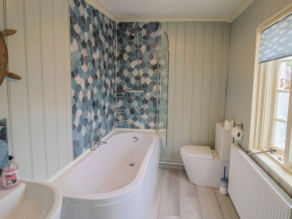 A bathroom with a bathtub, shower, toilet and sink at 5B Bridge Street Lyme Regis