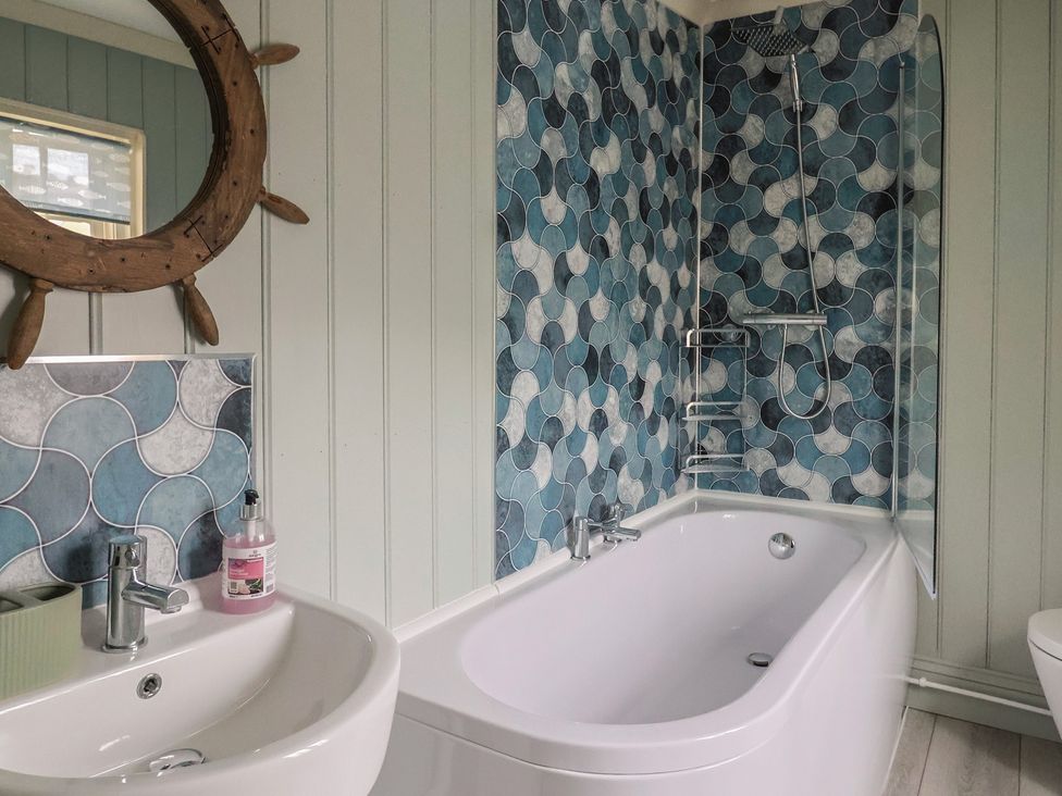 A bathroom with a bath, sink, and colorful tiles at 5B Bridge Street in Lyme Regis