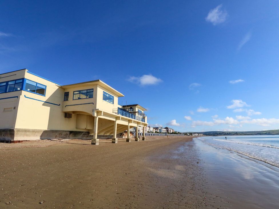 A beach with a building next to the water at 123 On The Sea - The Cubby Weymouth