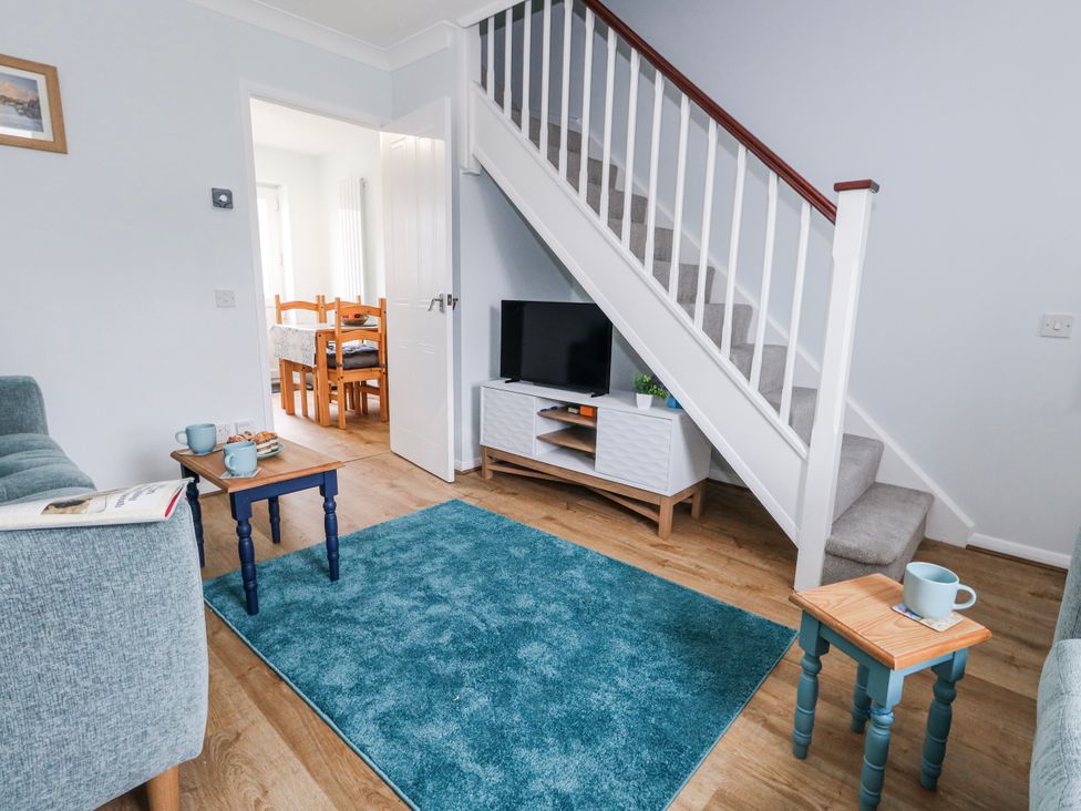A living room with a sofa, television, and coffee tables at 23 The Maltings in Weymouth