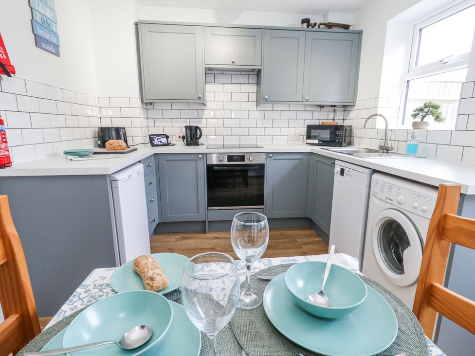 A kitchen with appliances and dining setup at 23 The Maltings in Weymouth