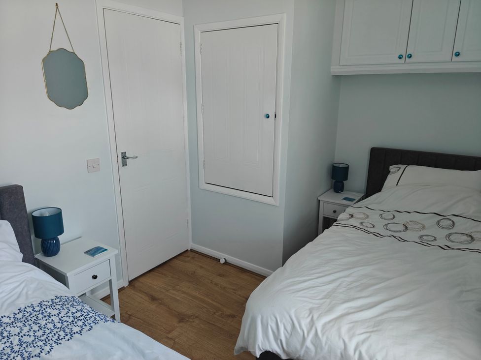 A bedroom with two beds and a nightstand at Dolphin Cottage in Weymouth