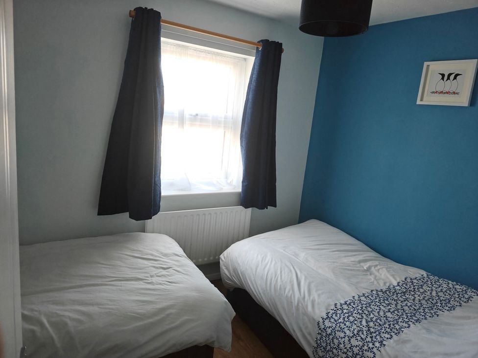 A bedroom with twin beds and a window at Dolphin Cottage in Weymouth