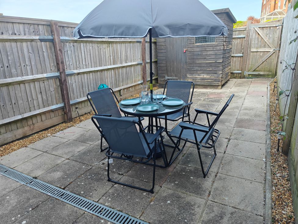 A patio with a table and chairs in the garden at Dolphin Cottage in Weymouth