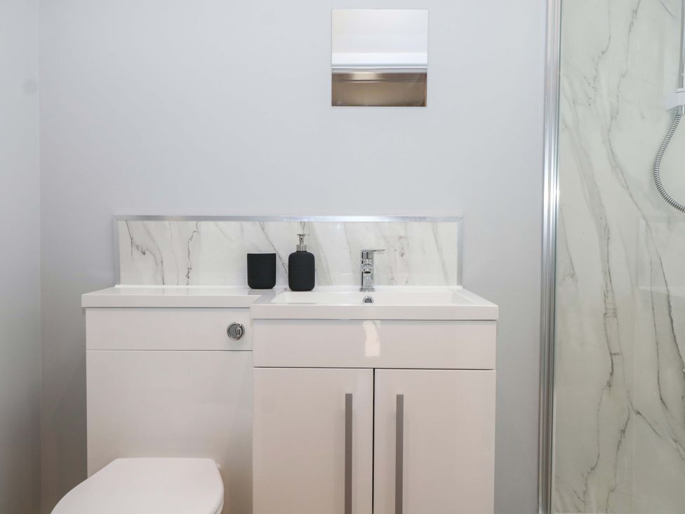 A bathroom with a sink, toilet, mirror, and shower at The Old Parlour in Southampton