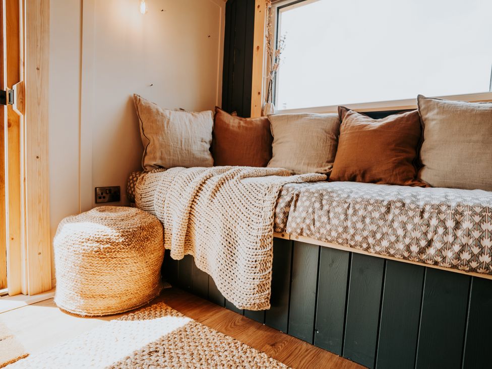 A living room with a sofa and cushions at Driftwood in Carreglefn near Llanfechell