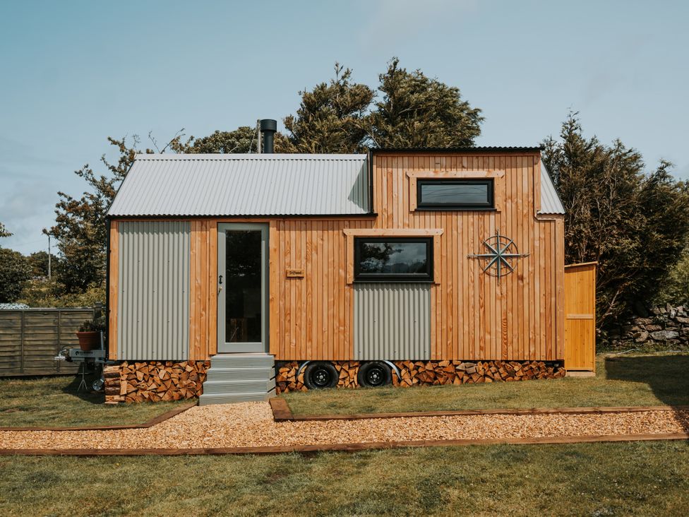 A tiny house with wooden exterior and metal roof at Rowan in Carreglefn near Llanfechell