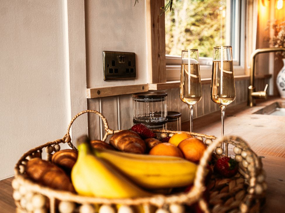 A kitchen with a basket of fruit and champagne glasses at Rowan in Carreglefn near Llanfechell