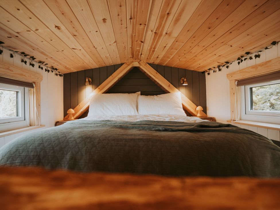 A bedroom with a bed and windows at Rowan in Carreglefn near Llanfechell