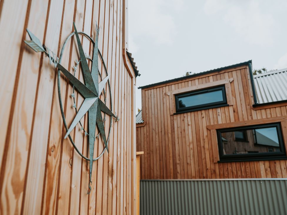 An exterior view featuring a compass on wood paneling at Rowan in Carreglefn near Llanfechell
