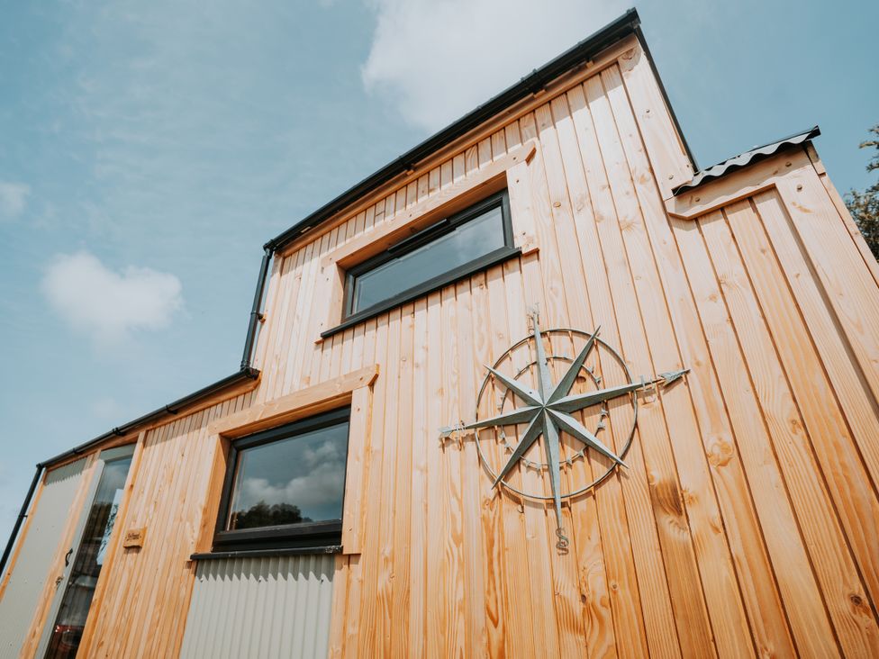 A wooden house exterior with windows and a compass decoration at Rowan, Carreglefn near Llanfechell