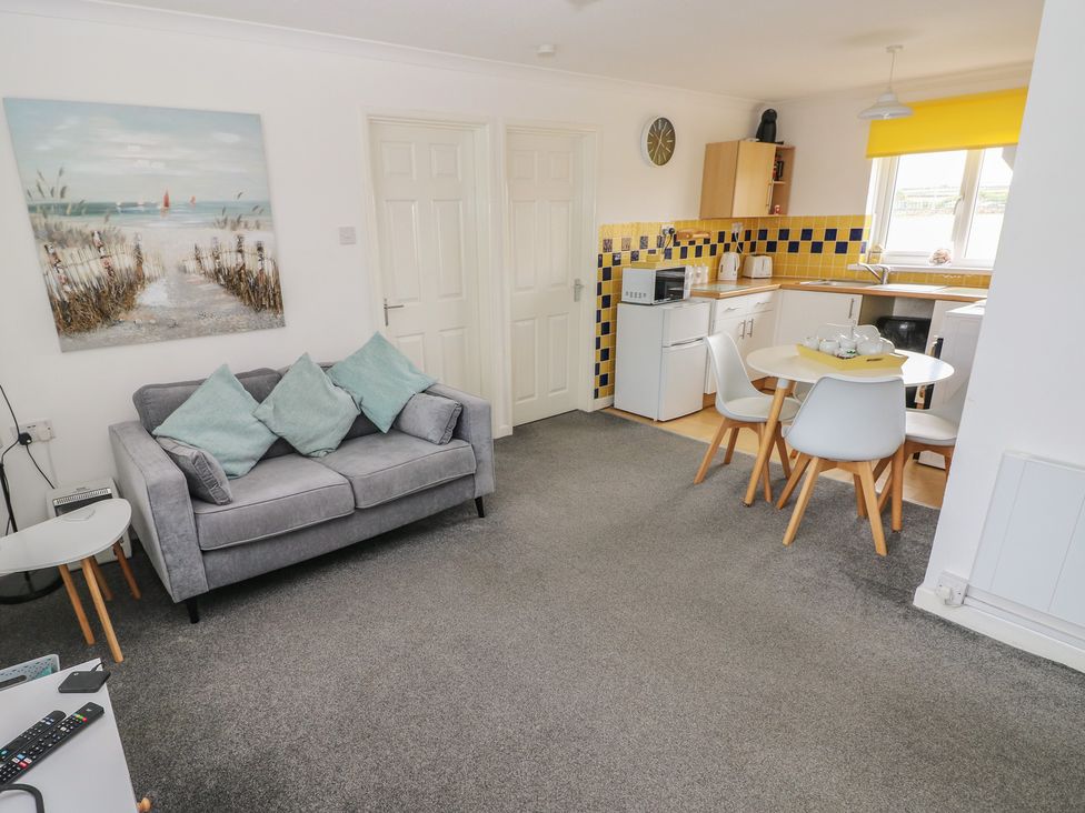 A living room with a couch and a kitchen area at Chalet 26 in Scurlage