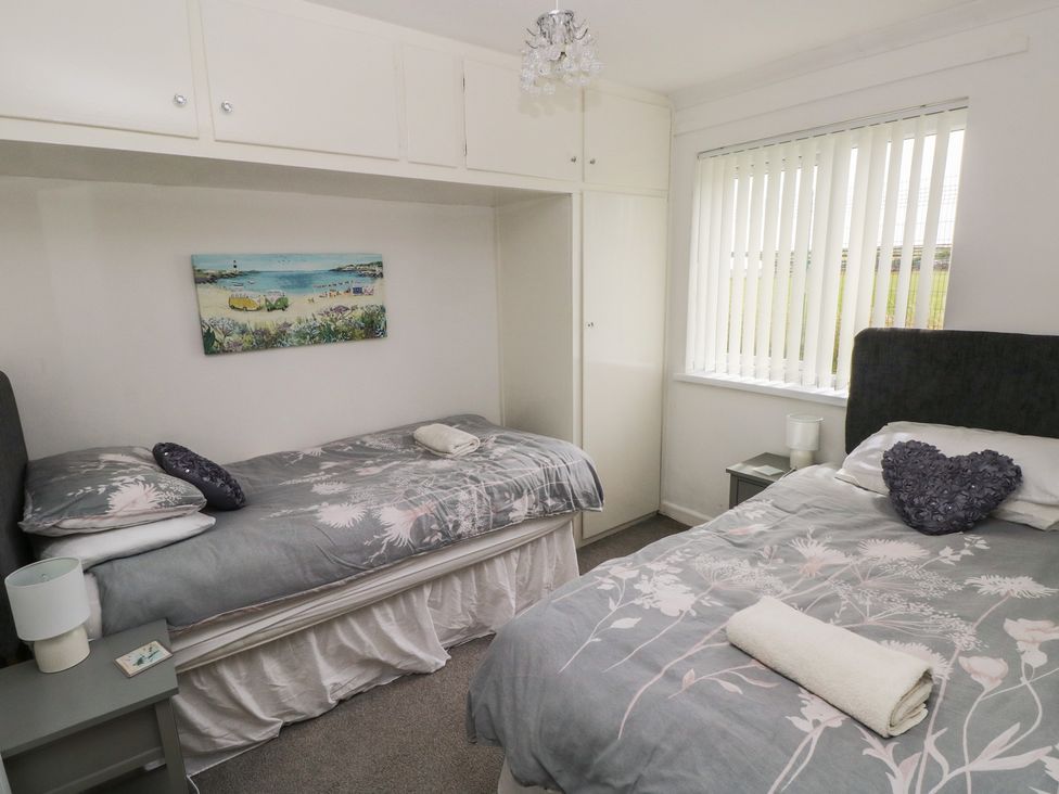 A bedroom with two beds and a nightstand at Chalet 26 in Scurlage