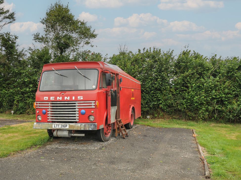 A red fire truck parked in a field at Dashing Dennis - 22 in Chapmanswell near Launceston