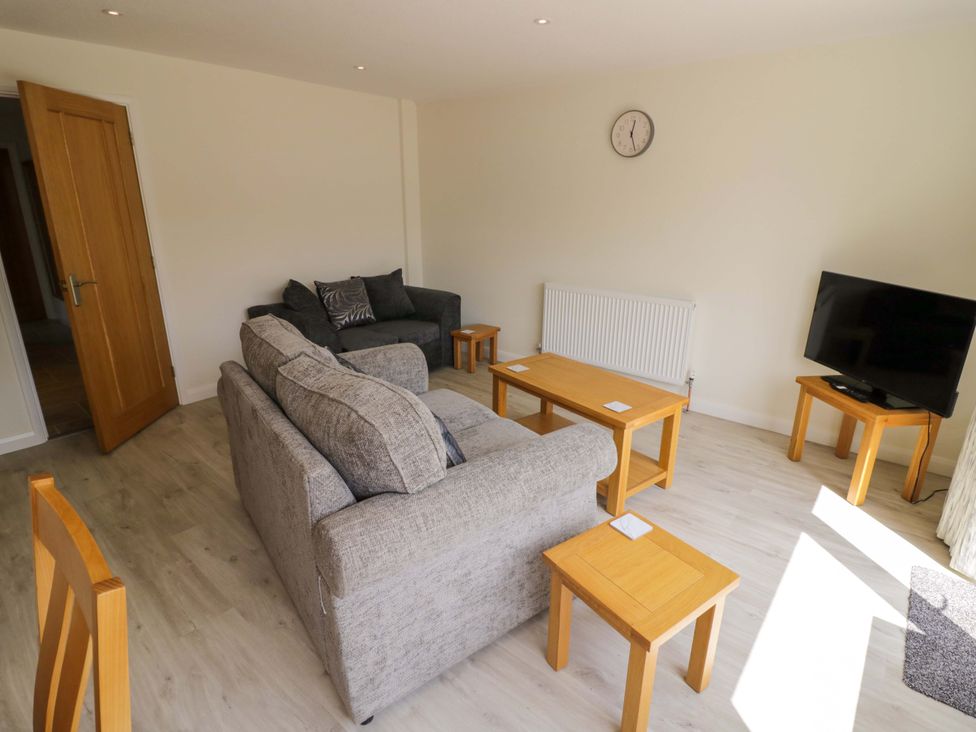 A living room with a sofa, armchair, coffee table, and television at 22 Old Chapel Close in Kidlington