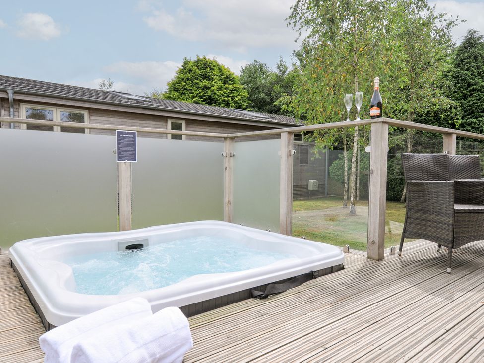 A hot tub on a wooden deck with champagne at 3 Meadow Retreat in Liskeard