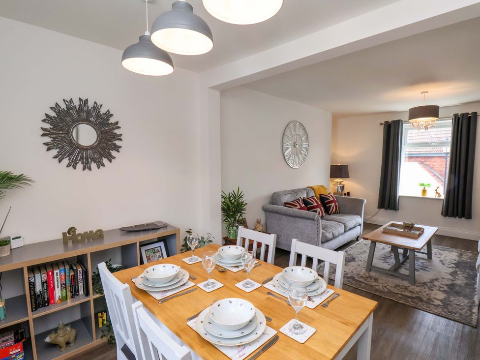 A dining area with a table and chairs adjacent to a living room at Postman’s Lodge in Middlesbrough