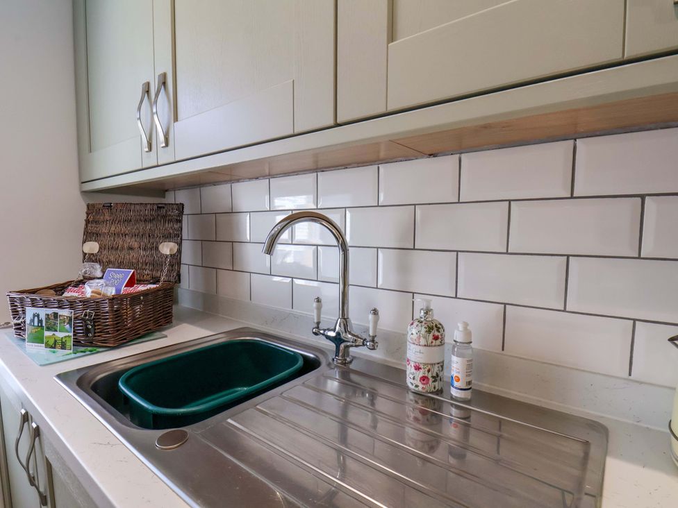 A kitchen sink with a basket and cleaning supplies at Postman’s Lodge in Middlesbrough