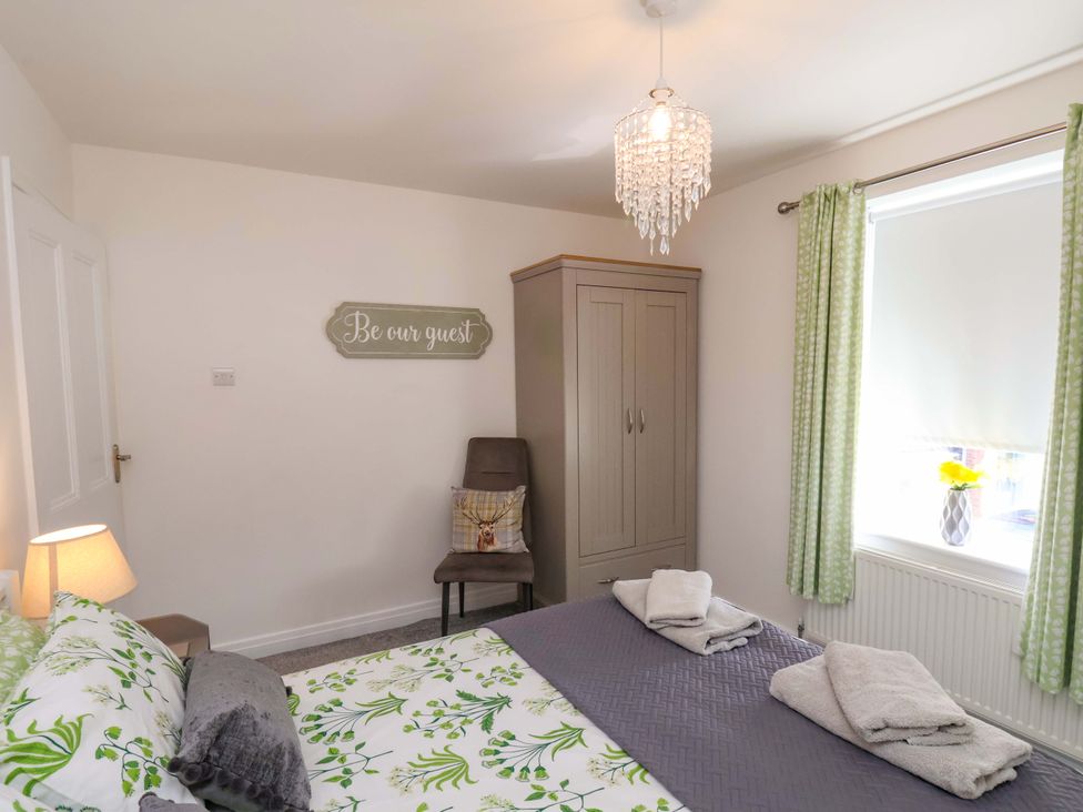 A bedroom with a bed, cabinet, chair, and window at Postman’s Lodge in Middlesbrough