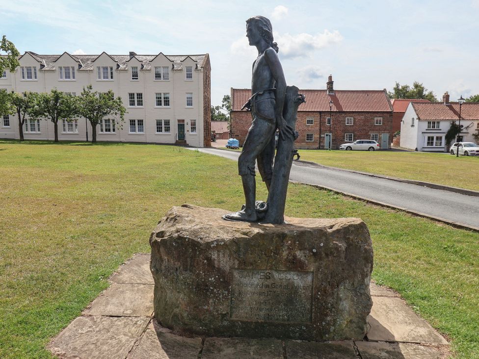 A statue on a stone base in a grass area at Postman’s Lodge in Great Ayton