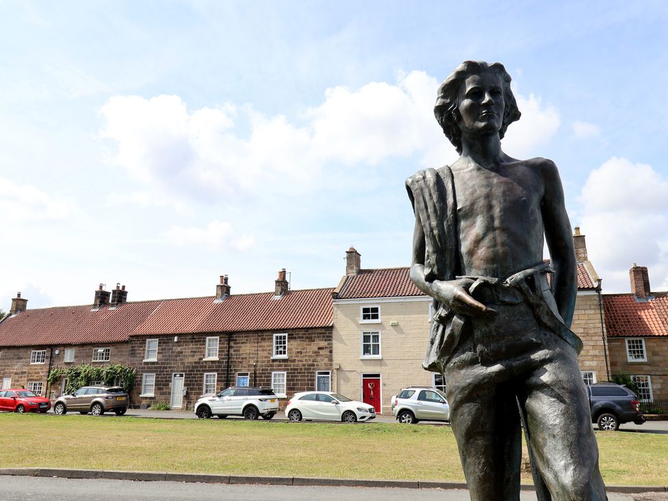 A statue with houses and cars in the background at Postman’s Lodge in Great Ayton