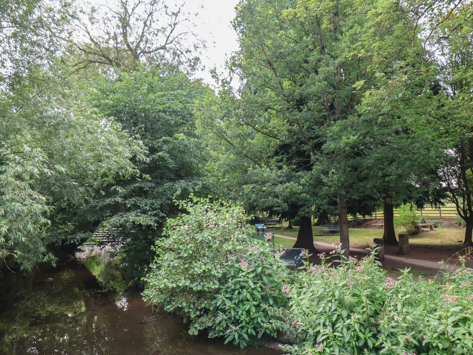 A park area with trees, bushes, and a stream at Postman’s Lodge in Great Ayton