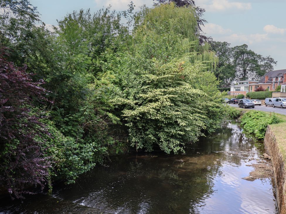 A river with trees and bushes beside a road at Postman’s Lodge in Great Ayton