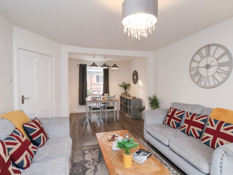 A living room with a coffee table and dining area at Postman’s Lodge in Great Ayton