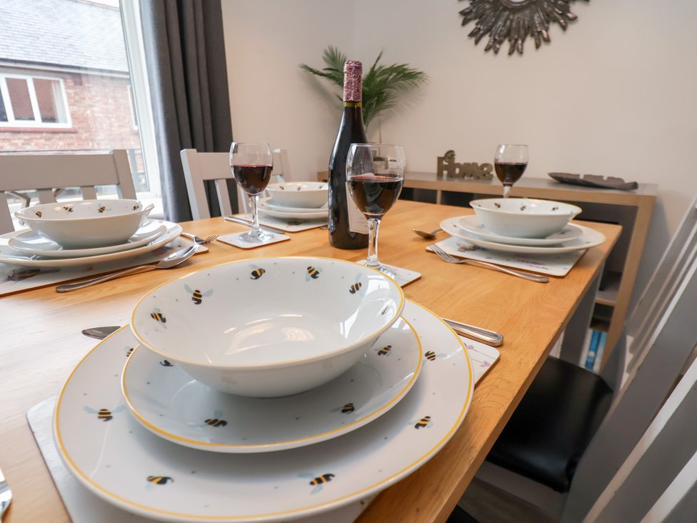 A dining table set with plates and wine glasses at Postman’s Lodge in Great Ayton