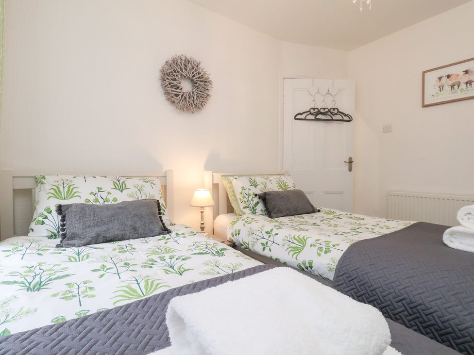 A bedroom with two beds and a door at Postman’s Lodge in Great Ayton