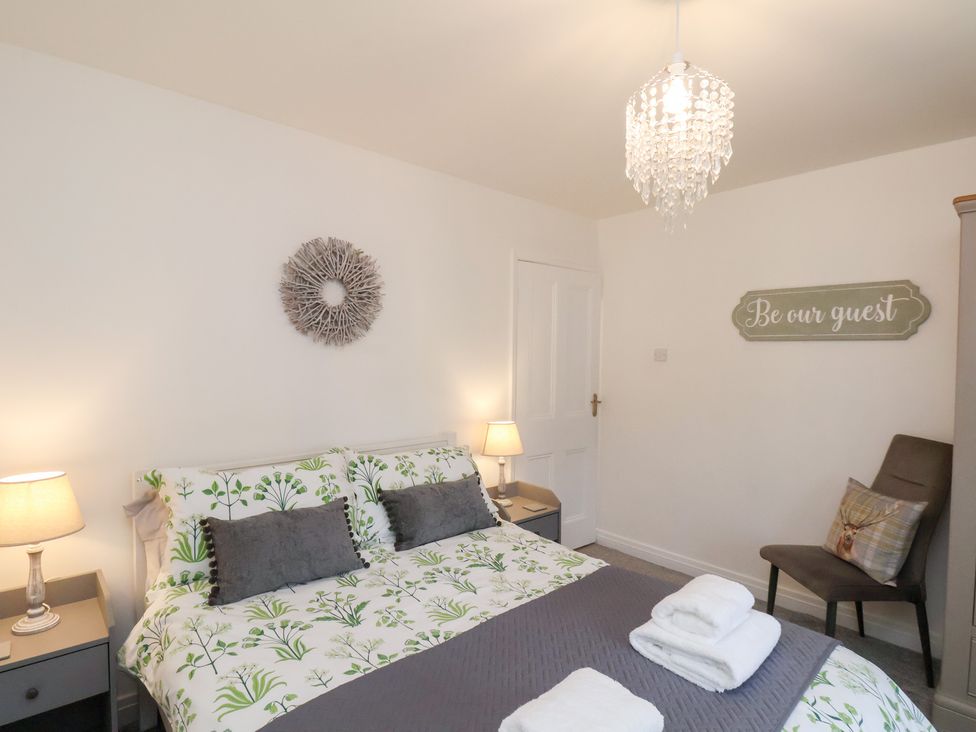 A bedroom with a bed, nightstands, and a chair at Postman’s Lodge in Great Ayton