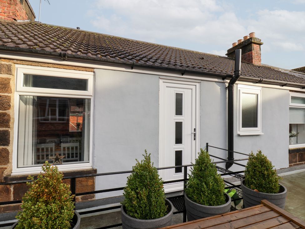 An outdoor view of a house with a door and plants at Postman’s Lodge in Great Ayton