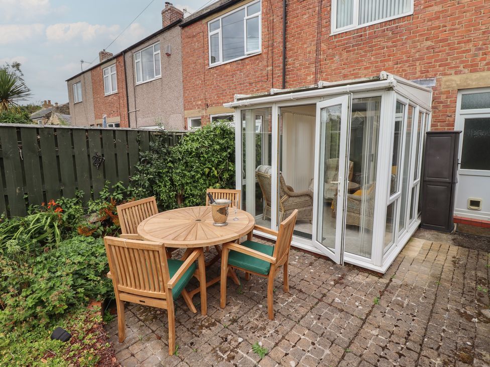 A garden with a table and chairs next to a conservatory at 5 Jackson Terrace Morpeth