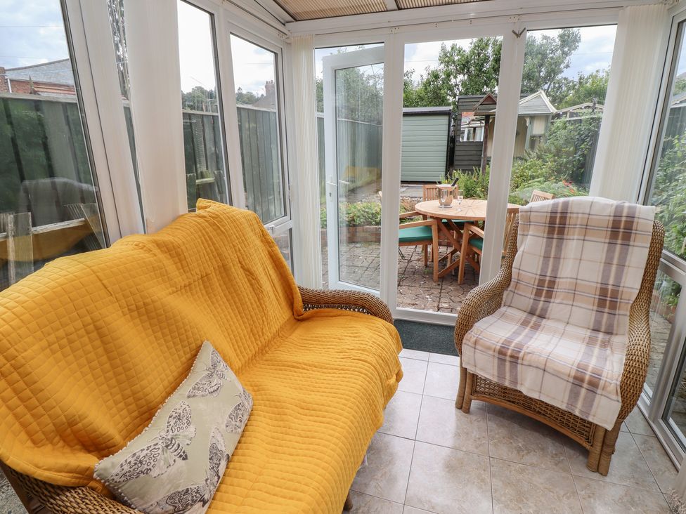 A conservatory with a sofa and armchair at 5 Jackson Terrace in Morpeth