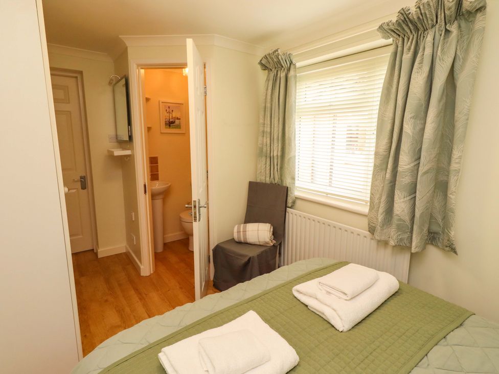 A bedroom with a bed and an adjoining bathroom at Rose Briar Cottage in Morpeth