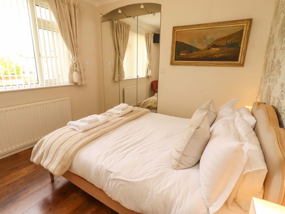 A bedroom with a bed and mirror at Rose Briar Cottage in Morpeth