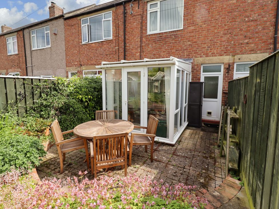 A garden with a conservatory and a table with chairs at Rose Briar Cottage Morpeth