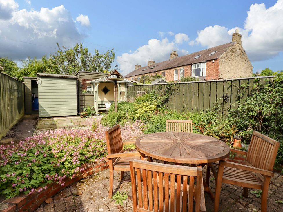 A garden with a table and chairs at Rose Briar Cottage in Morpeth