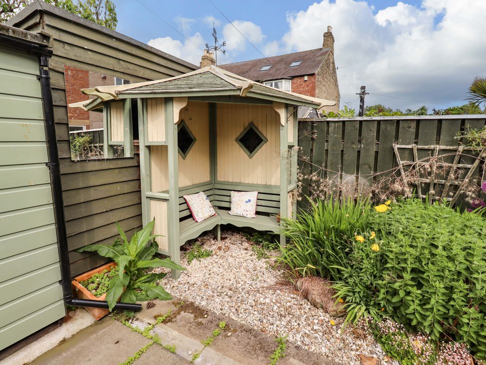 A garden seating area with a wooden structure at Rose Briar Cottage Morpeth