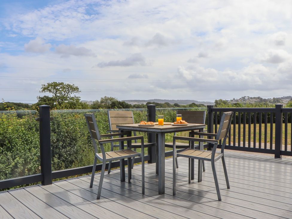 An outdoor dining area with a table and chairs at Maple Lodge in Teigngrace near Kingsteignton