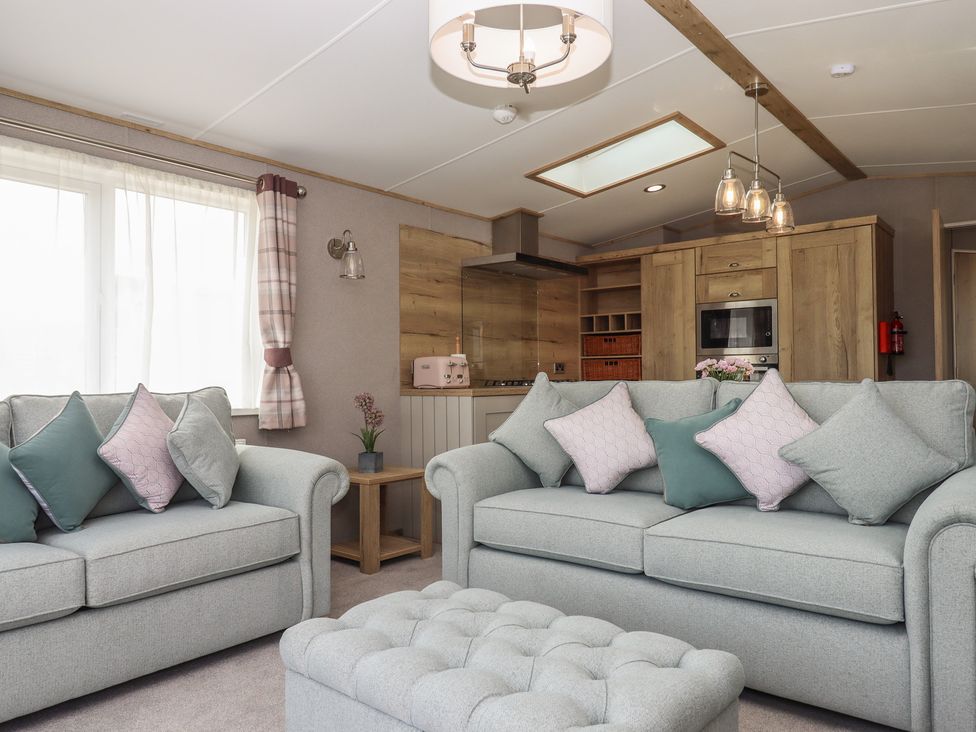 A living room with sofas and kitchen unit at Maple Lodge Teigngrace near Kingsteignton