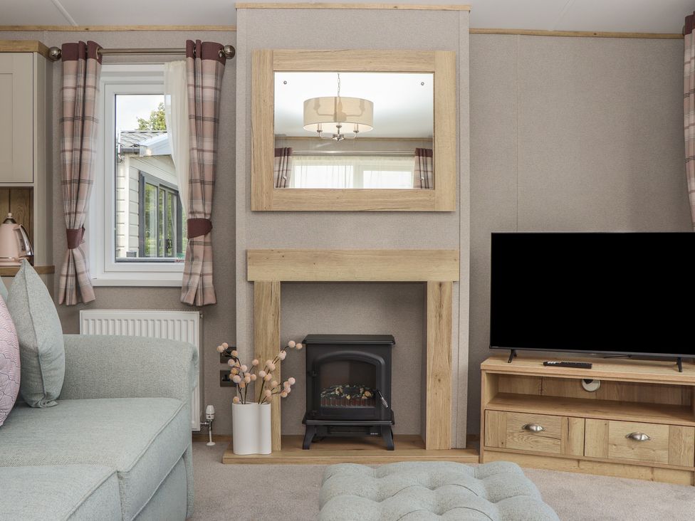 A living room with a fireplace and television at Maple Lodge Teigngrace near Kingsteignton
