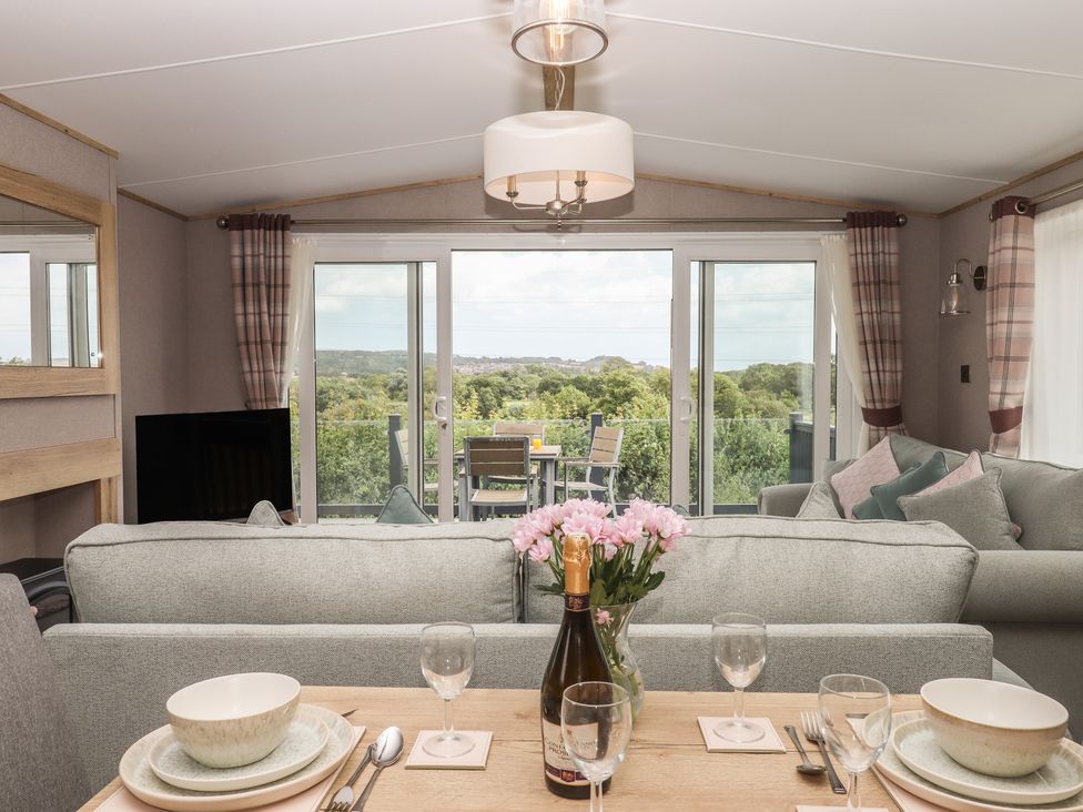 A living room with a view of the outdoor seating area at Maple Lodge in Teigngrace near Kingsteignton