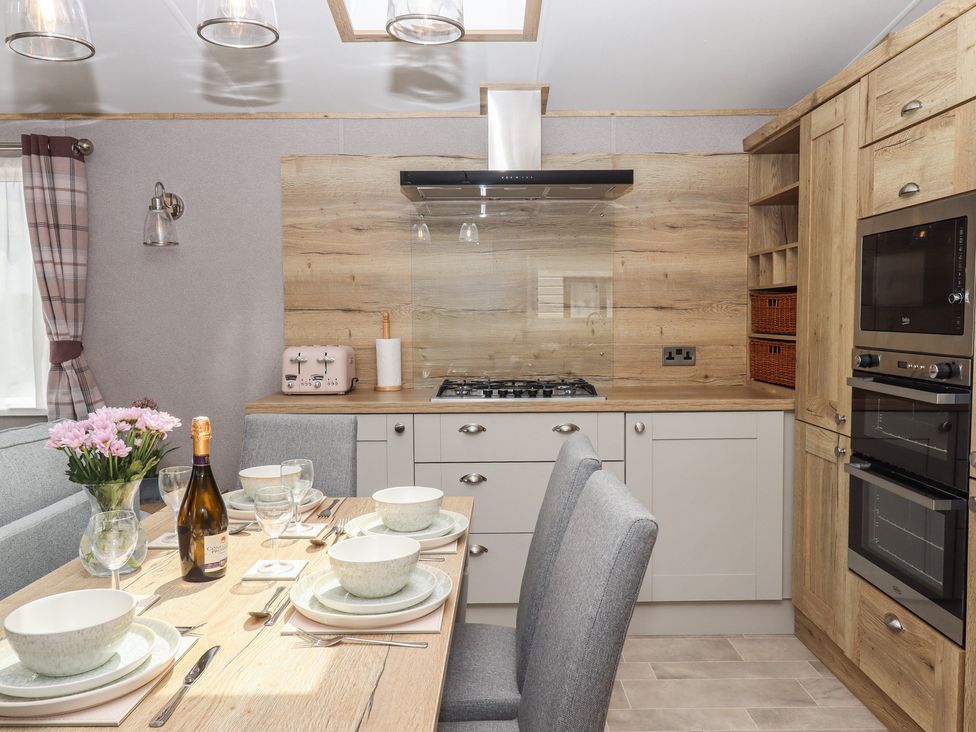 A kitchen with a dining area, stove, and cabinets at Maple Lodge Teigngrace near Kingsteignton