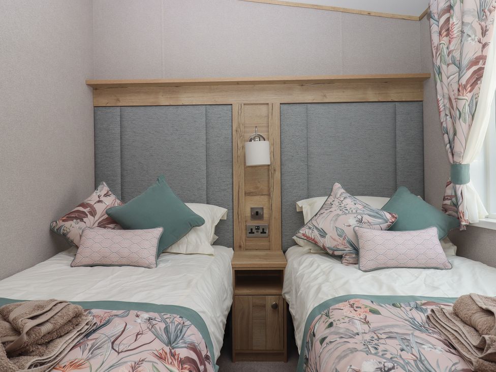 A bedroom with two beds and a bedside table at Maple Lodge Teigngrace near Kingsteignton