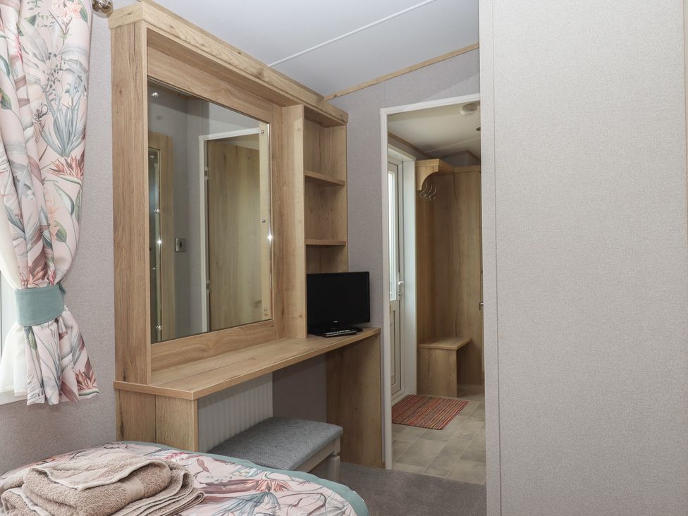 A bedroom with a mirror and shelf at Maple Lodge Teigngrace near Kingsteignton