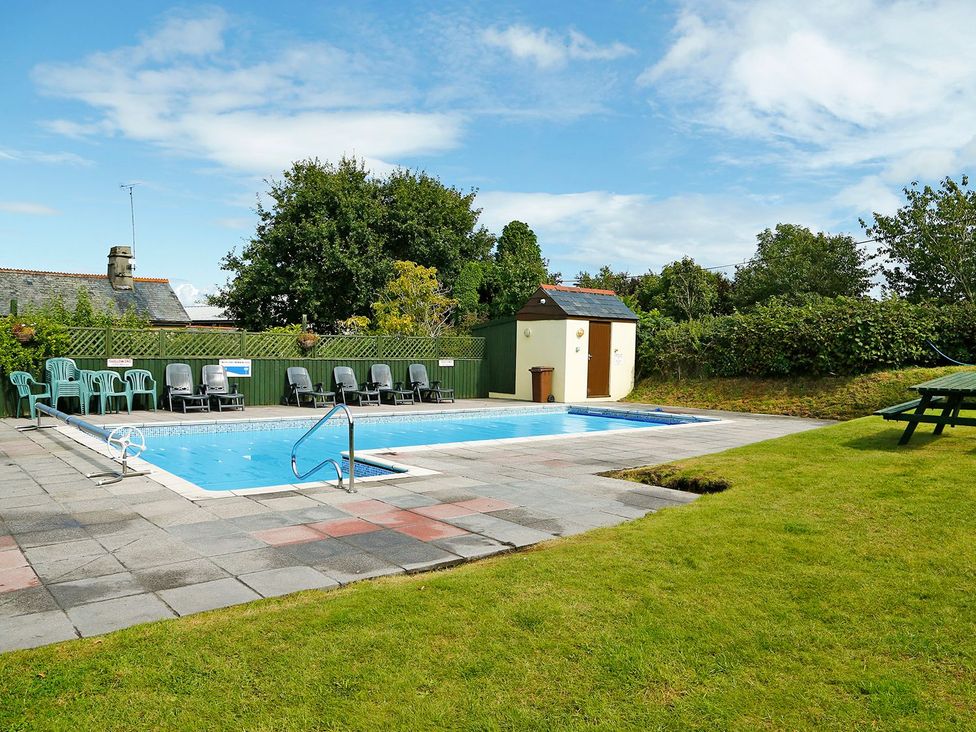 A swimming pool surrounded by chairs and a shed at Maple Lodge Teigngrace near Kingsteignton
