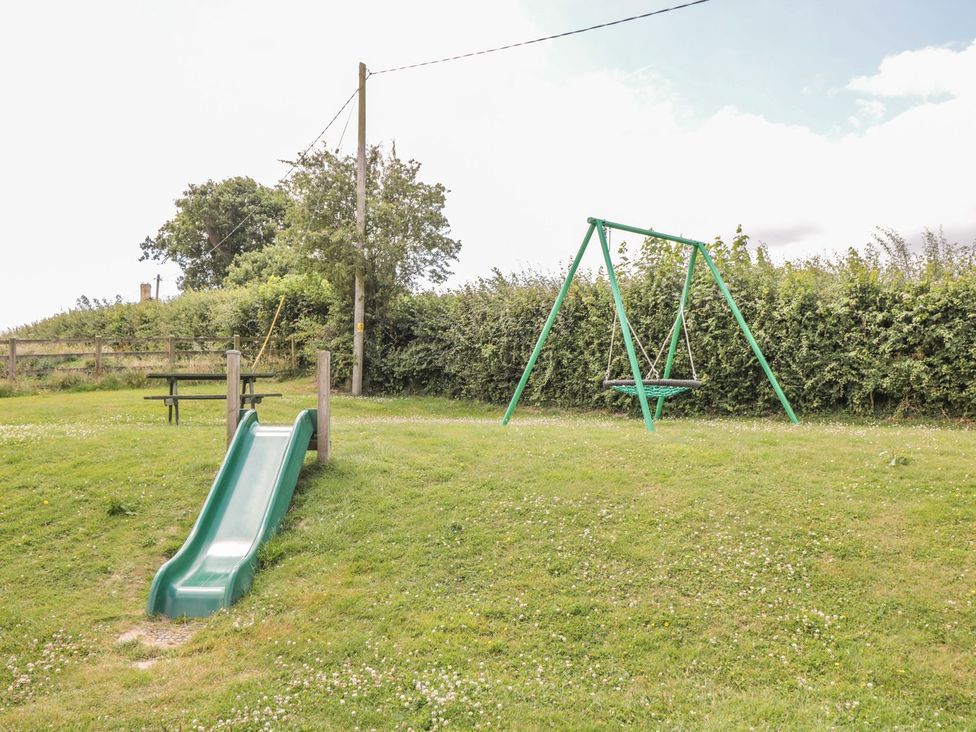 A slide and swing in a grassy outdoor area at Maple Lodge Teigngrace near Kingsteignton