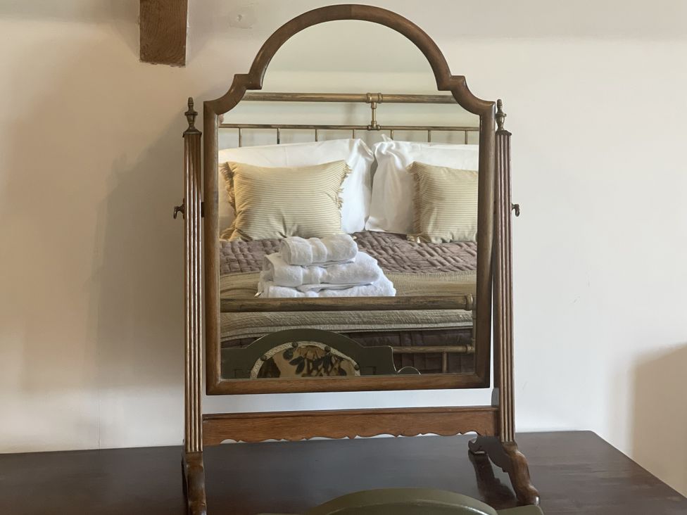 A mirror reflecting a bed with pillows and towels at Queensbury Loft in Par